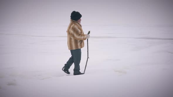 Side View Wide Shot Old Indigenous Man Strolling on Frozen Ocean Outdoors in Slow Motion