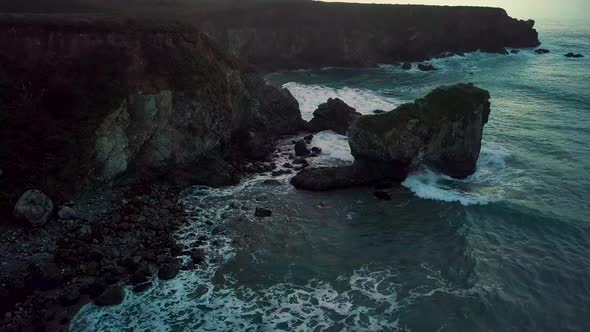 Rolling Pacific Ocean waves crash into rocky Sand Dollar Beach at dusk in Big Sur California