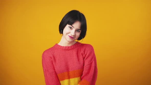 Cute Young Lady in Red Sweater Looking at Camera and Showing OK Gesture Orange Background