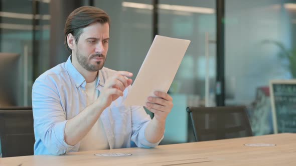 Mature Adult Man Reacting to Loss While Reading Documents