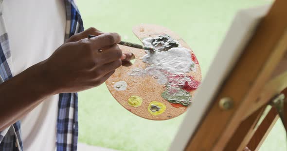 Video of african american senior man painting picture outside