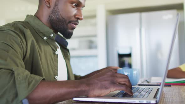 African american father and son doing homework and using a laptop together