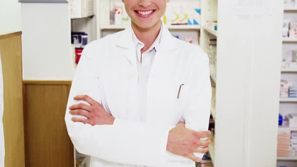 Pharmacist standing with arms crossed in pharmacy