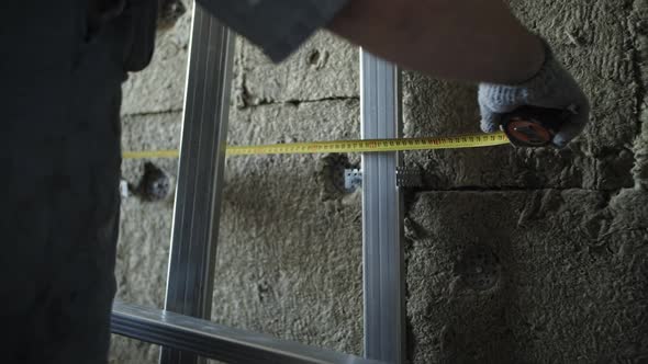 worker measures the wall with a tape measure