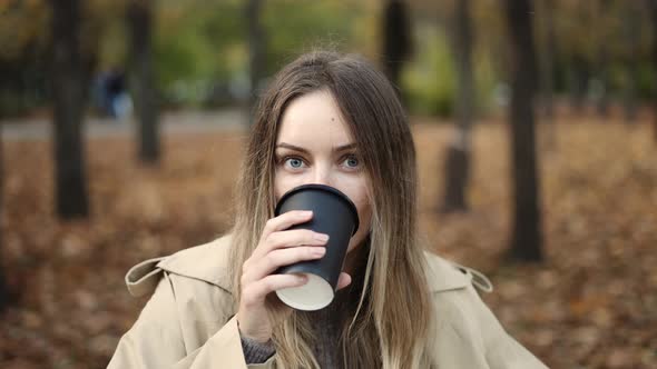 Portrait of a Blonde Woman Drinking Take Away Coffee in the Golden Autumn Park