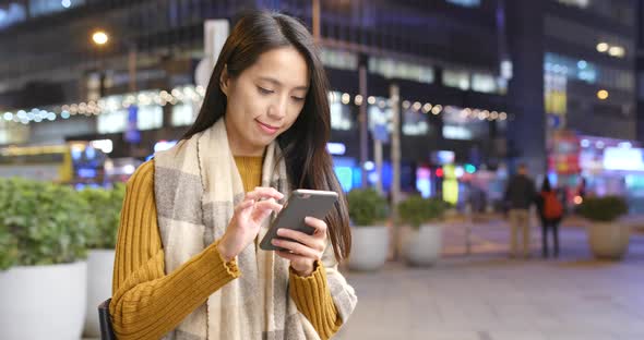 Woman working on cellphone in the city at night