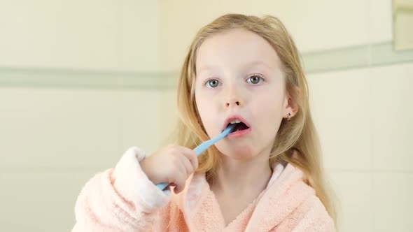 Happy Smiling Little Girl Brush Teeth Using Ultrasonic Electric Toothbrush in Bathroom at Home