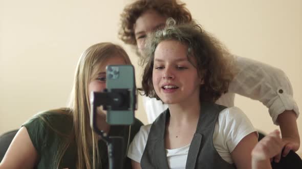 Three Teenage Schoolchildren Shoot a Funny Video for Social Networks Using a Smartphone and a