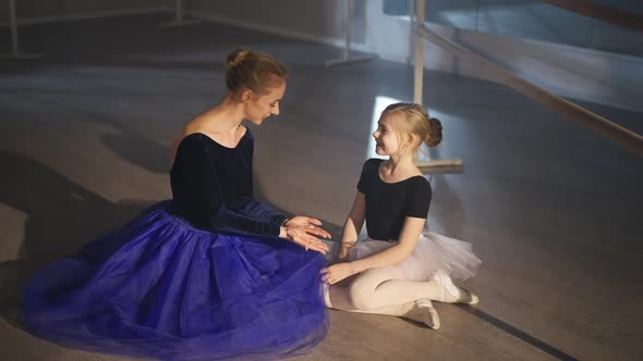Wide Shot of Happy Slim Gorgeous Professional Ballerina and Inspired Little Girl Sitting on Floor in