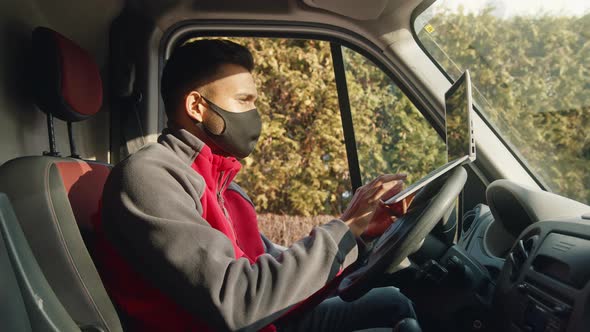 Young Indian Man with Cloth Face Mask Using Laptop in the Van