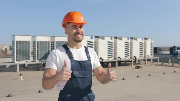 The Happy Engineer is Looking at the Camera and Showing Two Fingers Up