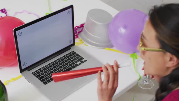 Happy asian woman with champagne making new year's eve video call on laptop with copy space