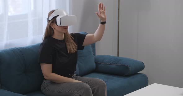 Young Woman Is Using Headmounted Display for Viewing Interior of Modern House Sitting on Couch in