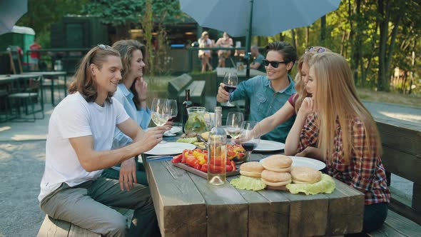 Friends Toasting With Drinks At Dinner Party Outdoors