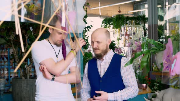 Two Men are Listening to Something on the Phone Both with Beards One of Them is Bald