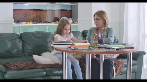 Mother Teaching Her Daughter As Sitting at the Table. Irritated Child Having Problems with Homework