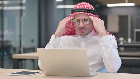 Middle Aged Arab Man with Laptop having Headache