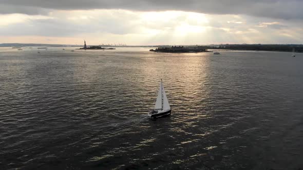 Aerial View of Sailboat During Sunset on the Hudson River with Liberty Island on the Background