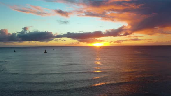 Fleet of Sailboats And Surfers Watch Beautiful Sunrise Off Waikiki Beach in Honolulu, Hawaii as they