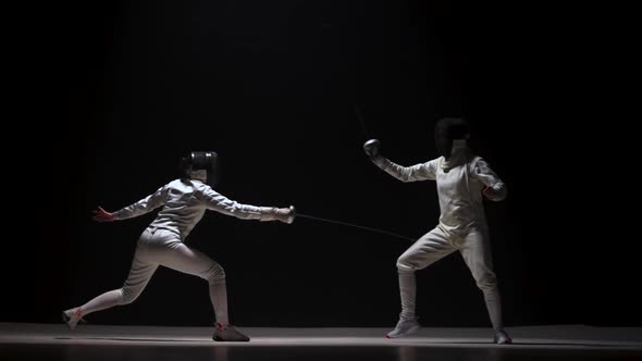 Training of Female Fencers with a Rapier on a Black Background