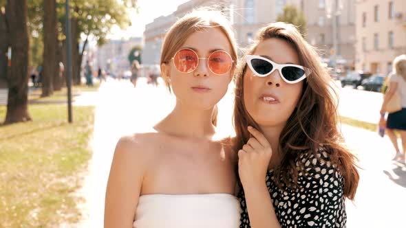 Portrait of two young beautiful smiling hipster girls in trendy summer clothes