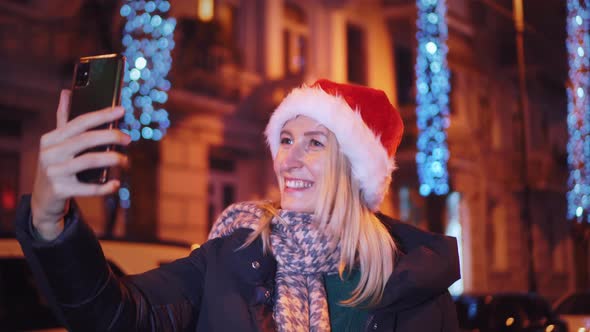 Young beautiful girl at Christmas to walk around city and take selfie. lights