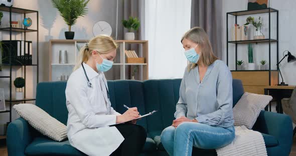 Doctor in Face Mask Visiting Her Patient at Home and Listening About Symptoms of Illness