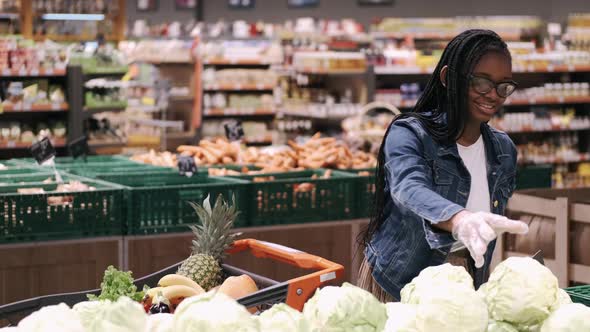African-American Young Woman in Mask Is Choosing Products in a Supermarket
