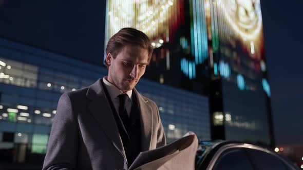 Portrait of a Young Businessman Standing Near a Black Car and Reads Financial Documents Top Manager