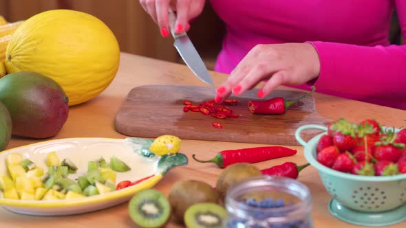 Woman in a Pink Blouse Chopping Spicy Red Chilli on a Table