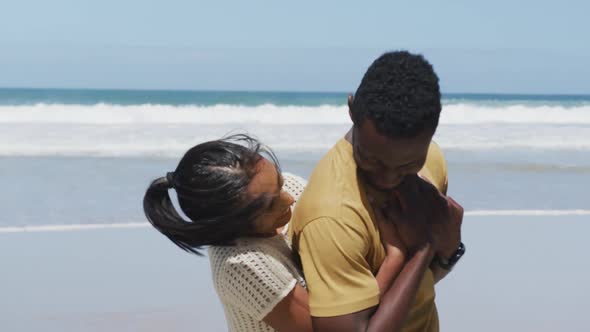 Happy african american couple hugging and embracing each other at the beach