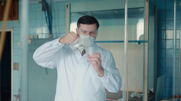 A medical worker in a medical suit and glasses holds in his hands cones doing tests.