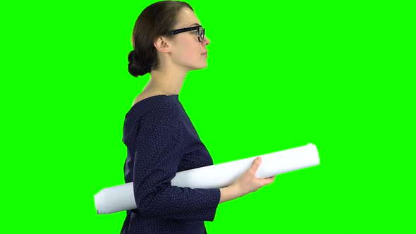 Designer Girl Comes with a Drawing in Her Hands. Green Screen. Side View