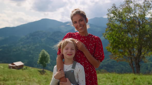 Mother Stroking Girl Head Standing in Front Mountains Closeup