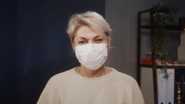 Portrait of Experienced Woman Doctor Wearing Medical Mask Looking in Camera Smiling Closeup of