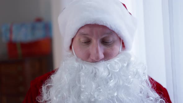 Headshot Portrait Confident Serious Santa Putting on Coronavirus Face Mask Looking at Camera