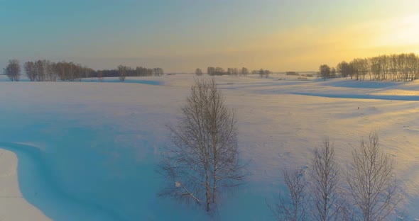 Aerial View of Cold Arctic Field Landscape Trees with Frost Snow Ice River and Sun Rays Over Horizon