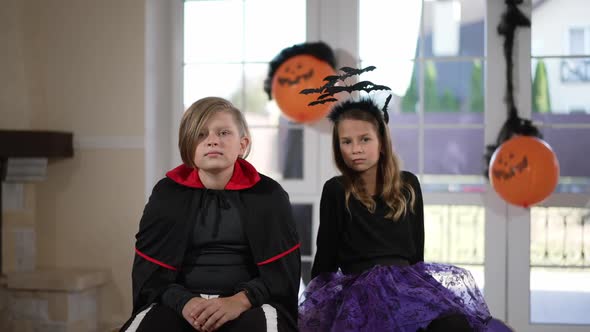 Caucasian Boy and Girl in Halloween Costumes Sitting in Living Room Watching TV As Woman Alien