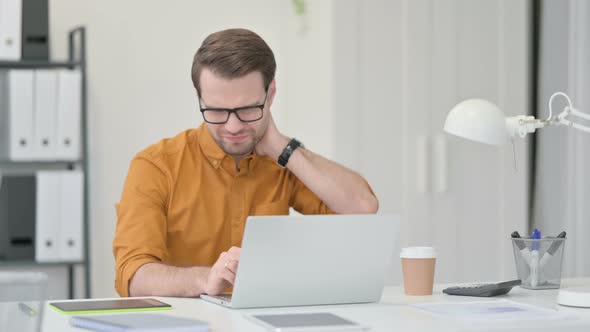 Young Man Having Neck Pain in Office 