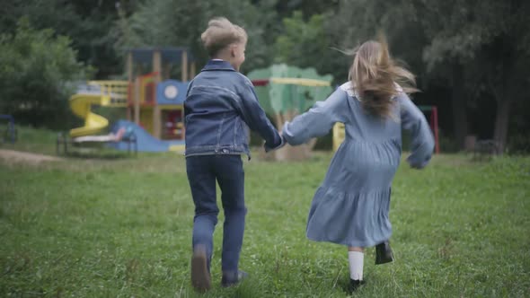 Wide Shot of Cheerful Carefree Children Running To Playground Holding Hands