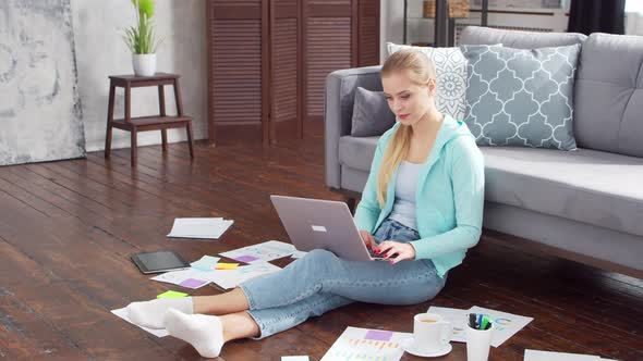 Young woman works with documents using a laptop at home.