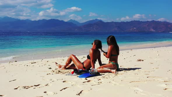 Sexy smiling ladies on vacation spending quality time at the beach on sunny blue and white sand 4K b