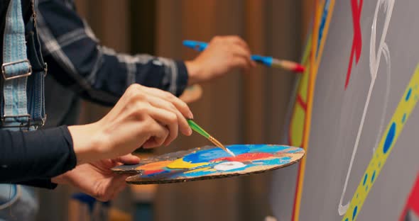 Closeup of Wooden Palette with Splotches of Paint Painter is Standing Close to Easel with