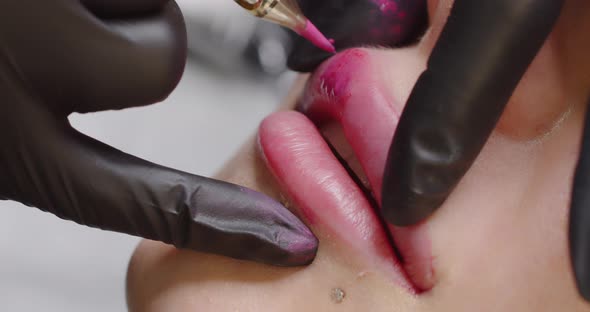 The Master Makes a Lip Tattoo for a Client in a Beauty Salon with a Special Device