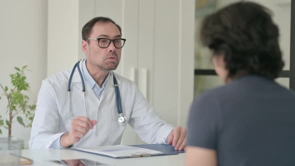 Middle Aged Doctor Talking to Patient in Office