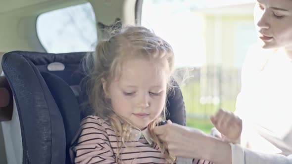 Mother Putting Daughter into Car Seat