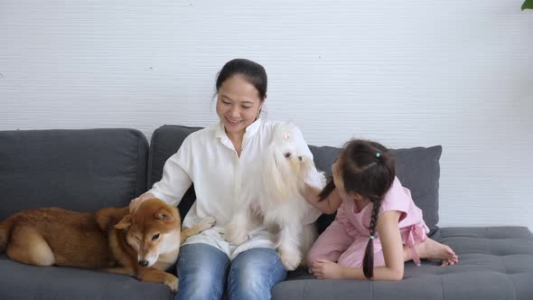 Asian mother and daughter patting pets at home