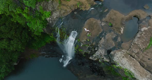 A Beautiful Woman in a White Dress on Top of a Waterfall in a Green Jungle Enjoys Her Victory
