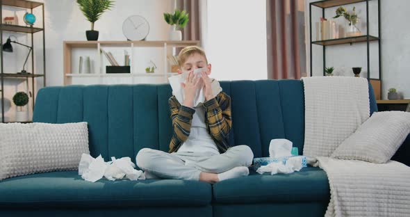 Tired Teen Boy with Influenza Blowing His Nose Using Napkin