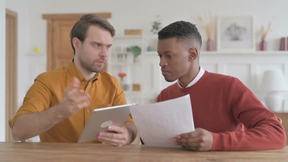 African Man and Young Man Working with Tablet and Documents